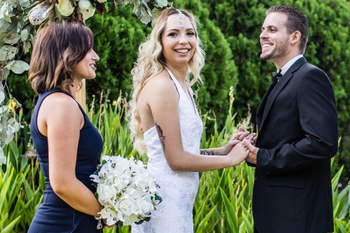 Bride and groom and bridesmaid smiling - Australian Stock Image