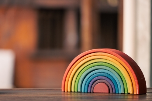 Brightly coloured wooden rainbow learning puzzle in nature-based playground environment - Australian Stock Image