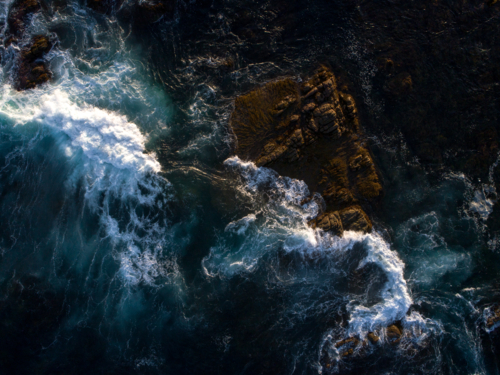 Broken wave crashes over exposed rock - Australian Stock Image