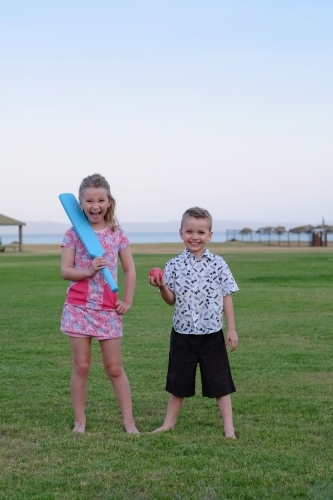 Brother and sister playing cricket in the park - Australian Stock Image