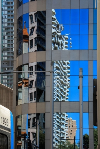 Buildings and blue sky reflected in high-rise windows in city street