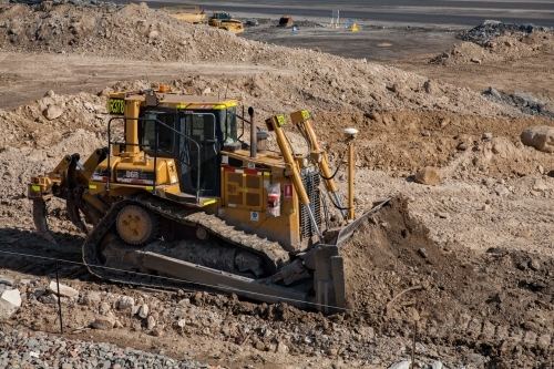 Bulldozer moving dirt beside open cut mine - Australian Stock Image