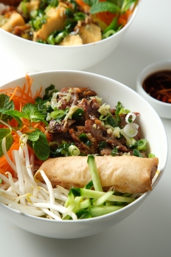 Bun Cha Gio bowls on a white countertop with a small dish of chili sauce on the side. - Australian Stock Image