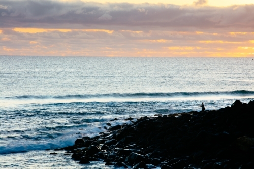 Burleigh Headland early in the morning with a silhouetted fisherman on the rocks - Australian Stock Image