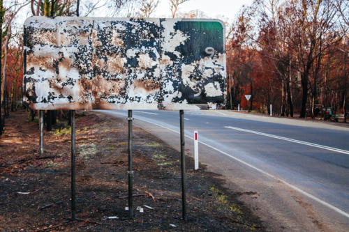 Burnt melted and peeling sign on road to Lake Mountain ski resort after 2009 Black Saturday bushfire - Australian Stock Image