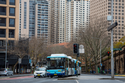 Bus at an intersection with tall buildings crowded around - Australian Stock Image