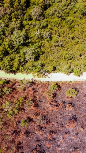 Bush fire aftermath drone shot in western Australia. One side of road healthy and green other burnt - Australian Stock Image