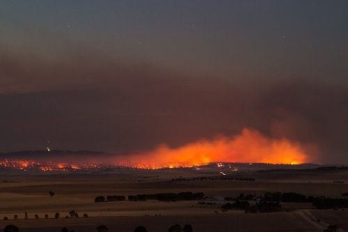 bushfire burning in rural area at dusk - Australian Stock Image
