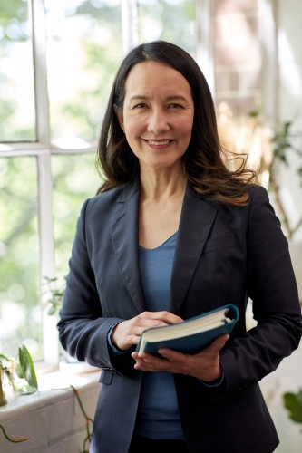 Business woman standing in studio holding a folder - Australian Stock Image