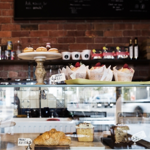 Cake display case in cafe with rustic wall behind - Australian Stock Image