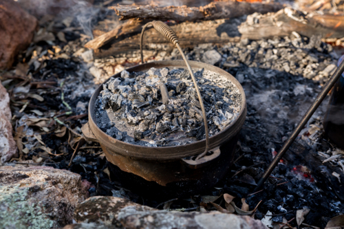 Camp oven in the ashes of a campfire - Australian Stock Image