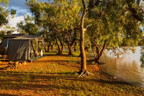 Campsite beside an outback lagoon in the early morning golden light - Australian Stock Image