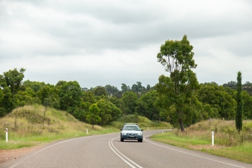 Car driving on sealed road with double lines on overcast day - Australian Stock Image