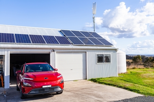 Car driving out from garage shed powered by electricity generated with solar and wind power - Australian Stock Image