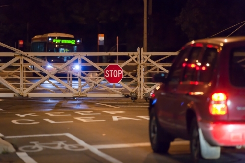 car waiting at rail crossing at night - Australian Stock Image