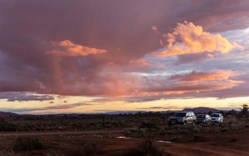 cars by dirt road at sunset in outback - Australian Stock Image