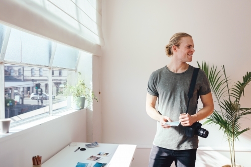 Casual photographer at work looking at someone off camera - Australian Stock Image