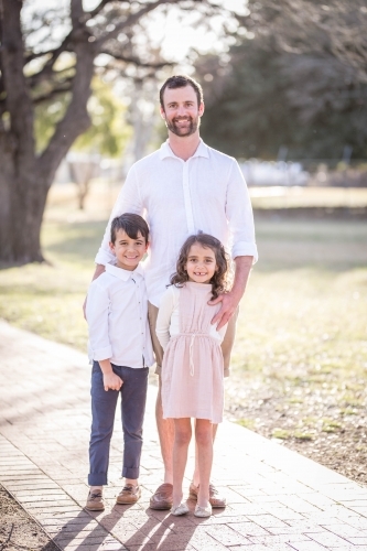 Caucasian man standing with twin mixed race aboriginal caucasian children - Australian Stock Image