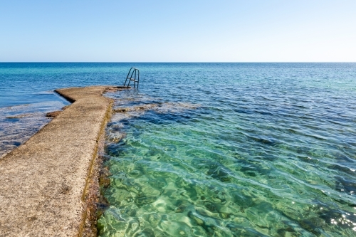 cement path to steps into blue sea - Australian Stock Image