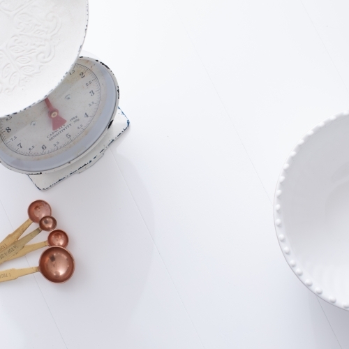 Ceramic bowl, measuring spoons and scales on white background - Australian Stock Image