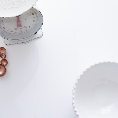 Ceramic bowl, measuring spoons and scales on white background - Australian Stock Image