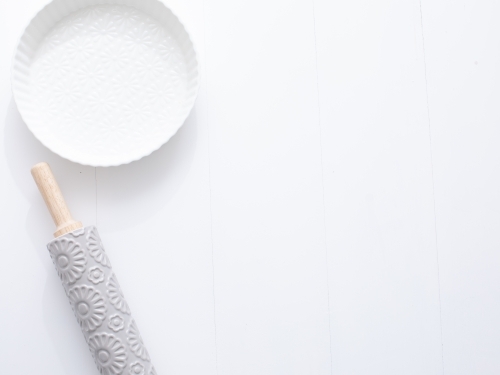 Ceramic pie dish and rolling pin on blank background - Australian Stock Image