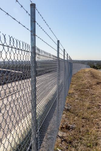 Chainwire and barbed wire fence - Australian Stock Image