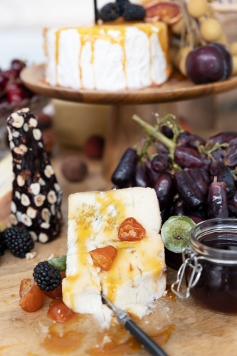 cheese board filled with cheeses and fruits - Australian Stock Image