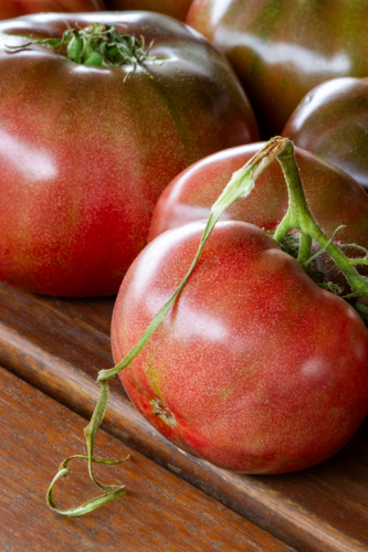 Cherokee Purple tomatoes on wooden table. - Australian Stock Image