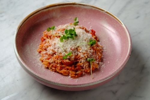 Cherry tomato sugo risoni in a pink bowl - Australian Stock Image