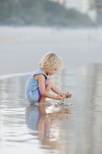 Child digging in the sand on Gold Coast beach - Australian Stock Image