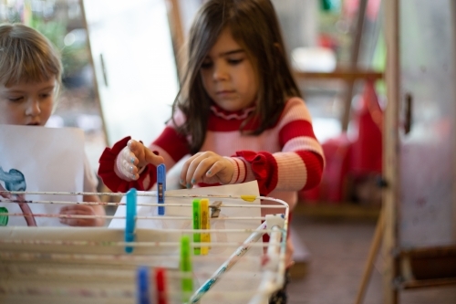 Child hanging a painting with pegs - Australian Stock Image