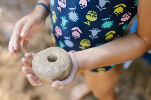 Child holding stone with hole - Australian Stock Image