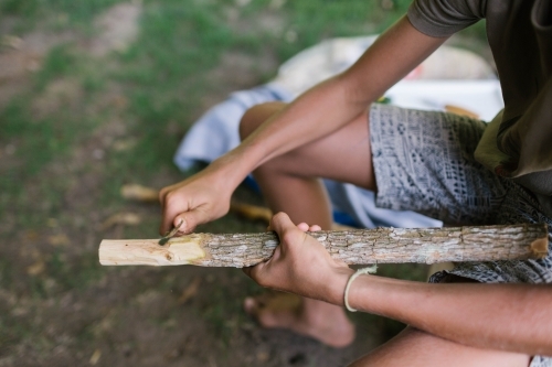 Child's hands carving the end of a stick - Australian Stock Image