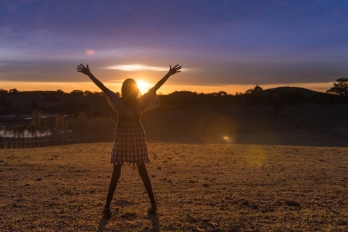 child standing in silhouette against the sunrise - Australian Stock Image