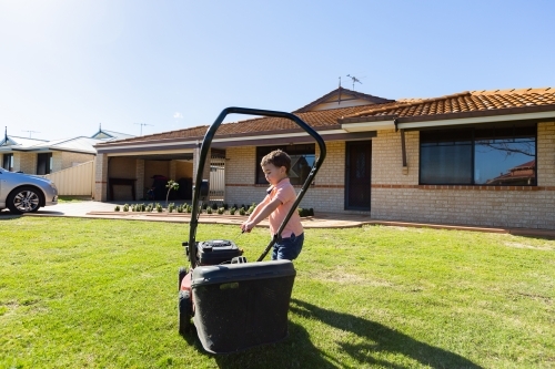 child trying to start lawnmower - Australian Stock Image