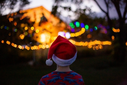 child wearing a santa hat looking at a christmas light display - Australian Stock Image