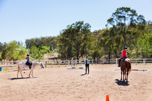 Children doing stretches during riding lesson with instructor - Australian Stock Image