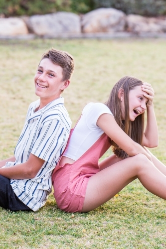 Children sitting back to back laughing - Australian Stock Image