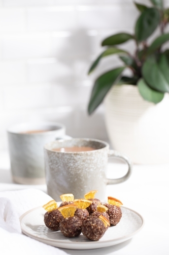 Chocolate protein balls on a white kitchen bench with two mugs - Australian Stock Image