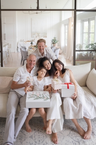 Christmas family photo on couch with presents - Australian Stock Image