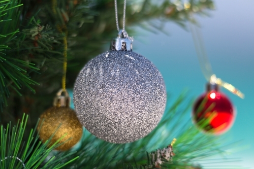 Christmas tree decorated with colourful baubles on the beach in summer - Australian Stock Image