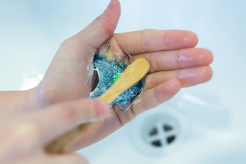 Cleaning orthodontic retainer at sink - Australian Stock Image