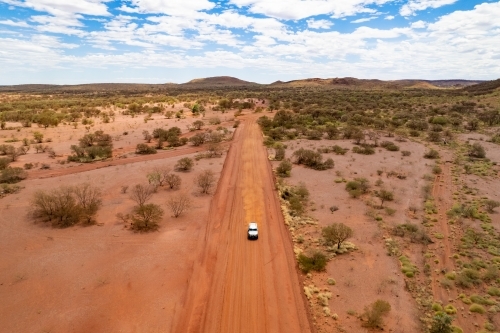 Close up aerial view of a 4WD driving down an isolated dirt track in the outback - Australian Stock Image