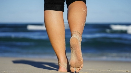 Close up low angle of feet walking away on the beach