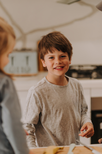 Close-up of a happy young boy standing near the kitchen counter. - Australian Stock Image