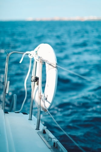 Close up of a life preserver attached to the wire railing of a boat on the water - Australian Stock Image