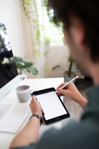 Close-up of a man using a stylus pen on e-device showing screen - Australian Stock Image