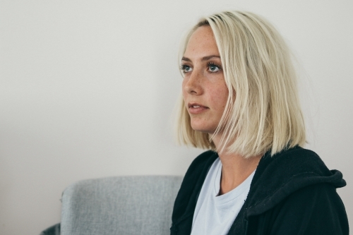 Close up of a seated young blonde woman looking away - Australian Stock Image