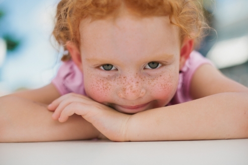 Close up of a young girl resting on her arms - Australian Stock Image